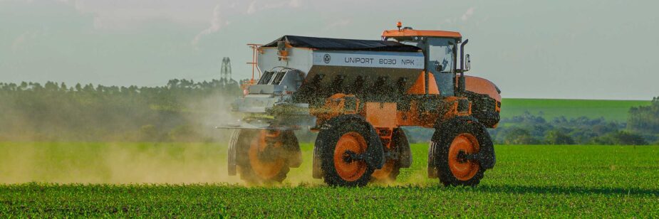 Tractor agrícola esparciendo fertilizante en un cultivo.