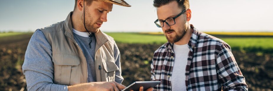 Dos hombres conversando sobre la economía en tierras agrícolas.