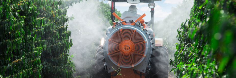Pulverización en el café con equipo asistido por aire acoplado a un tractor entre hileras de cafetos.